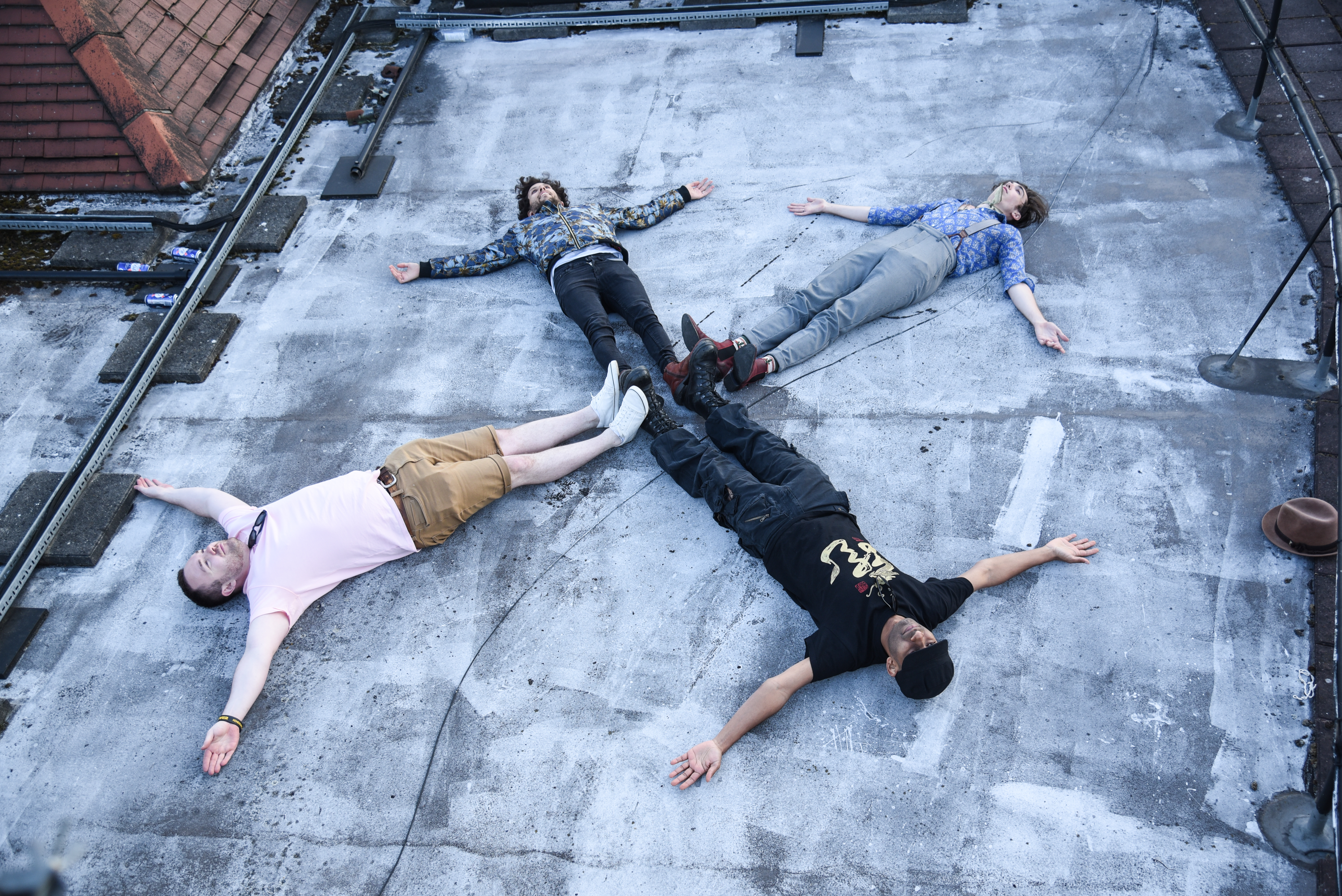Four band members lying on ground in star shape